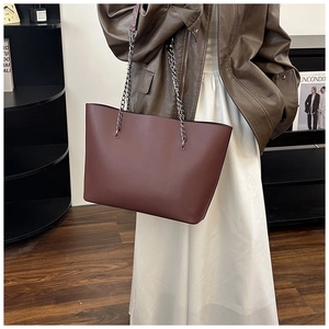 Detail of dark brown leather tote bag showing textured surface and metallic chain strap