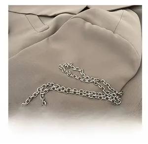 Close-up of bright silver metal chain strap and sequin fabric detail on handbag