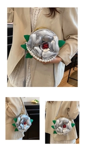 Close-up of 3D silver camellia flower bag with pearl trim and green leaf detail