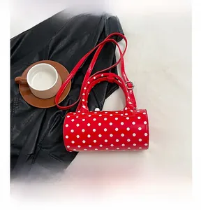 Détail d'un sac cylindrique rouge à pois avec veste en cuir et tasse de café