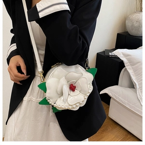 Detailed view of white 3D flower bag with red center, pearl trim and leather strap