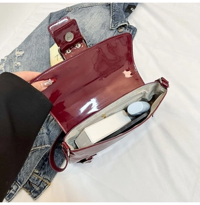 Vue intérieure du sac bandoulière en cuir verni bordeaux avec téléphone et objets