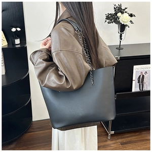 Detail of matte black tote bag showing metal chain strap and large capacity in lifestyle set