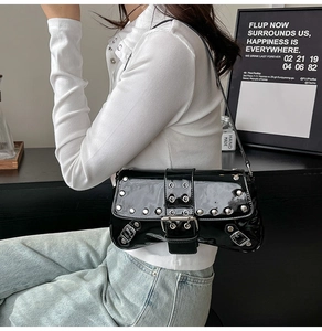Détail du sac baguette en cuir verni noir avec des clous et une boucle argentée
