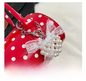 Détails du sac à bandoulière rouge à pois avec breloques perles et nœuds en dentelle
