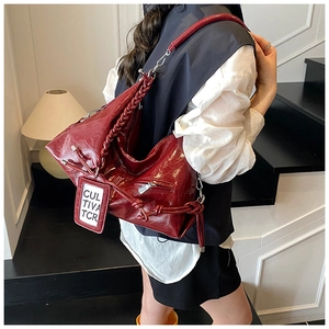 Détail du grand sac cabas bordeaux avec bandoulière tressée et texture brillante