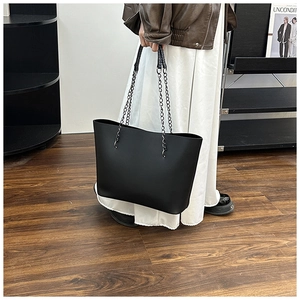 Minimalist black tote bag with chain strap shown in a modern lifestyle setting