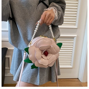 Detailed shot of pink 3D camellia flower bag with pearl handle and leather strap