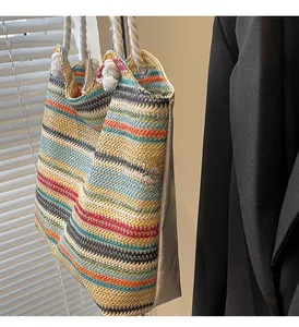 Detail of colorful striped straw tote bag featuring white woven rope handles and texture