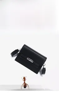 Detail of lightweight black leather shoulder bag showing 0.46KG weight and silver lock
