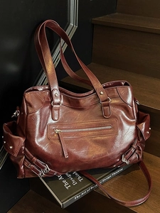 Retro burgundy oversized tote bag with rivets and stud detail on dark wooden steps