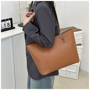 Detail of a brown leather tote bag with a sleek gunmetal chain strap for women