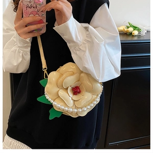 Detailed view of 3D floral crossbody bag with cream petals and white pearl trim detail