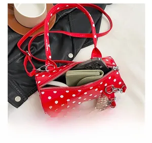 Vue de la capacité interne du sac cylindre rouge à pois avec téléphone et portefeuille