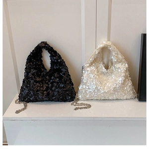 Close-up of black and white sequin handbags with metallic chain straps in a studio setting