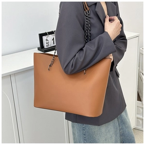 Brown leather tote bag with stylish metal chain strap shown from a side view for women