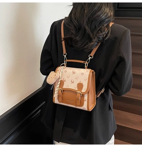 Detail view of mini backpack with deer pattern and plush bear charm on model