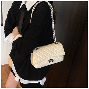 Detail of beige quilted crossbody bag with silver chain strap and turn-lock closure