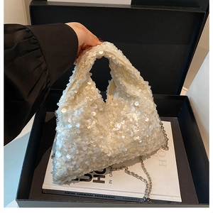 Detail of white sequin handbag featuring glossy round sequins and silver metal chain strap