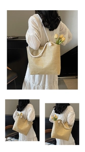 Detail of hand-woven straw tote with thick white rope handles and decorative pompom