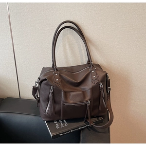 Dettaglio della grande borsa tote marrone scuro con texture litchi e tre zip argento