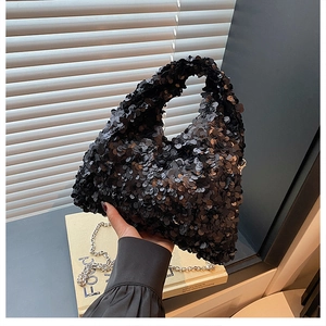 Detail of shimmering black sequin handbag with chic silver metal chain link handle