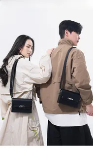 Detailed view of black leather crossbody bag featuring silver metallic twist lock closure