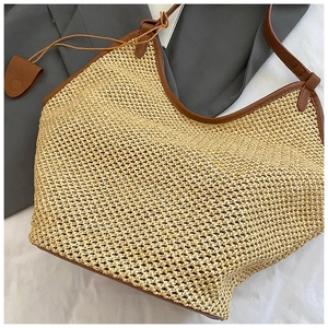 Detail of woven straw tote bag featuring leather handles and textured artisan stitching