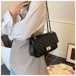 Close-up of quilted black leather crossbody bag with silver chain strap and metal clasp