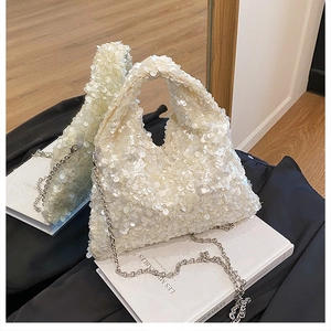 Close-up of shimmering pearlescent sequins and silver chain on a stylish white tote bag