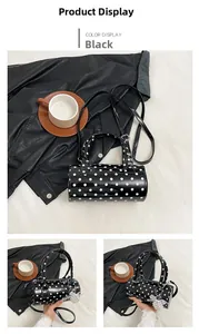 Détail du sac cylindrique noir à pois avec une finition brillante et breloque en perles