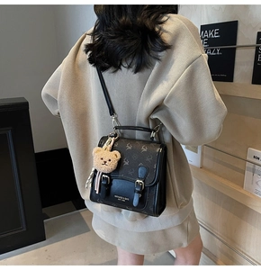 Detail of vintage black patchwork handbag with elk print and cute plush bear charm