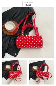 Détail du sac cylindrique rouge à pois avec breloque perle et finition brillante