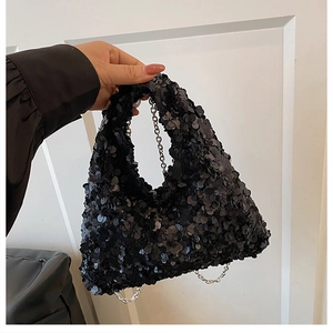 Detail of black sequined handbag showing textured shimmer surface and silver chain strap