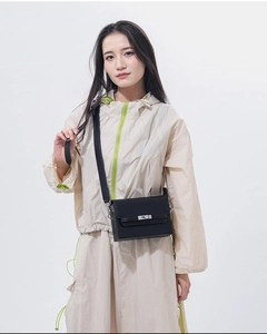 Detail of a black leather Kelly bag with silver metal lock on a casual beige outfit