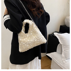 Macro detail of white sequin texture and metal chain strap on minimalist cloud bag