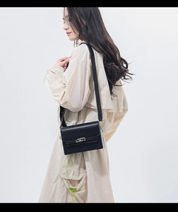 Classic black leather crossbody bag featuring a rotating metal lock on a female model