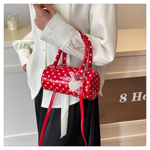 Detail of red polka dot cylinder handbag with pearl heart charm and lace accent