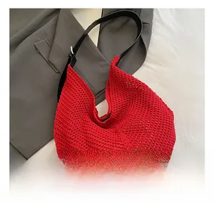 Detail of red woven hobo bag with contrast black leather strap and metal buckle
