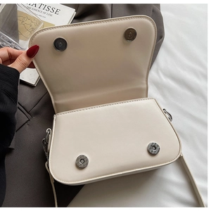 Close-up of minimalist beige leather crossbody bag with dual silver magnetic snap buttons