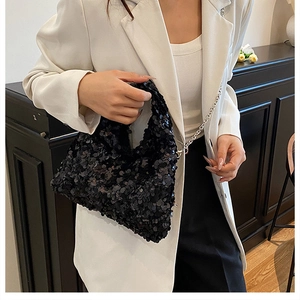 Fashionable black sequin hobo bag with silver chain strap worn by a model in a white blazer