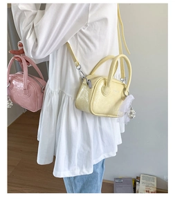 Detailansicht der pastellrosa und gelben Lackleder-Bowlingtaschen mit Perlenanhängern