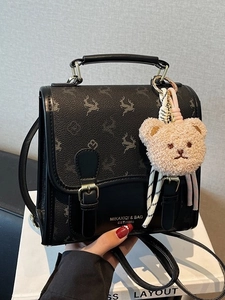 Chic black mini crossbody backpack featuring leather canvas patchwork and bear charm