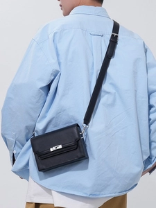 Minimalist black rectangle leather crossbody bag with silver twist lock on male model
