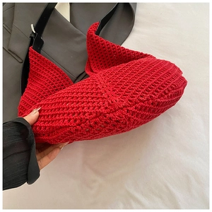 Detail of red hollow knit tote with black leather strap and silver metal buckle
