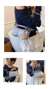 Detail of light blue croc-embossed handbag with metal twist lock and cute bear charm