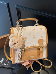 Beige and brown mini commuter backpack with bear charm and decorative buckle straps