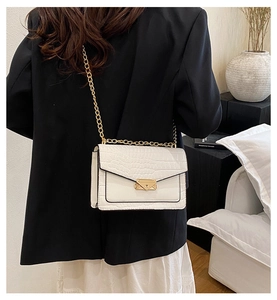 Detailed back view of a white crocodile texture chain bag styled in a chic interior