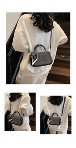 Close-up of contrast color handbag with decorative scarf on handle and silver hardware