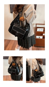 Detail of glossy black oil wax leather shoulder bag with a brown plush dog charm